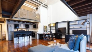 A modern open-plan living area with a kitchen, dining space, and a sofa with cushions. - Loft Bandiello by BarbarHouse (Milano)