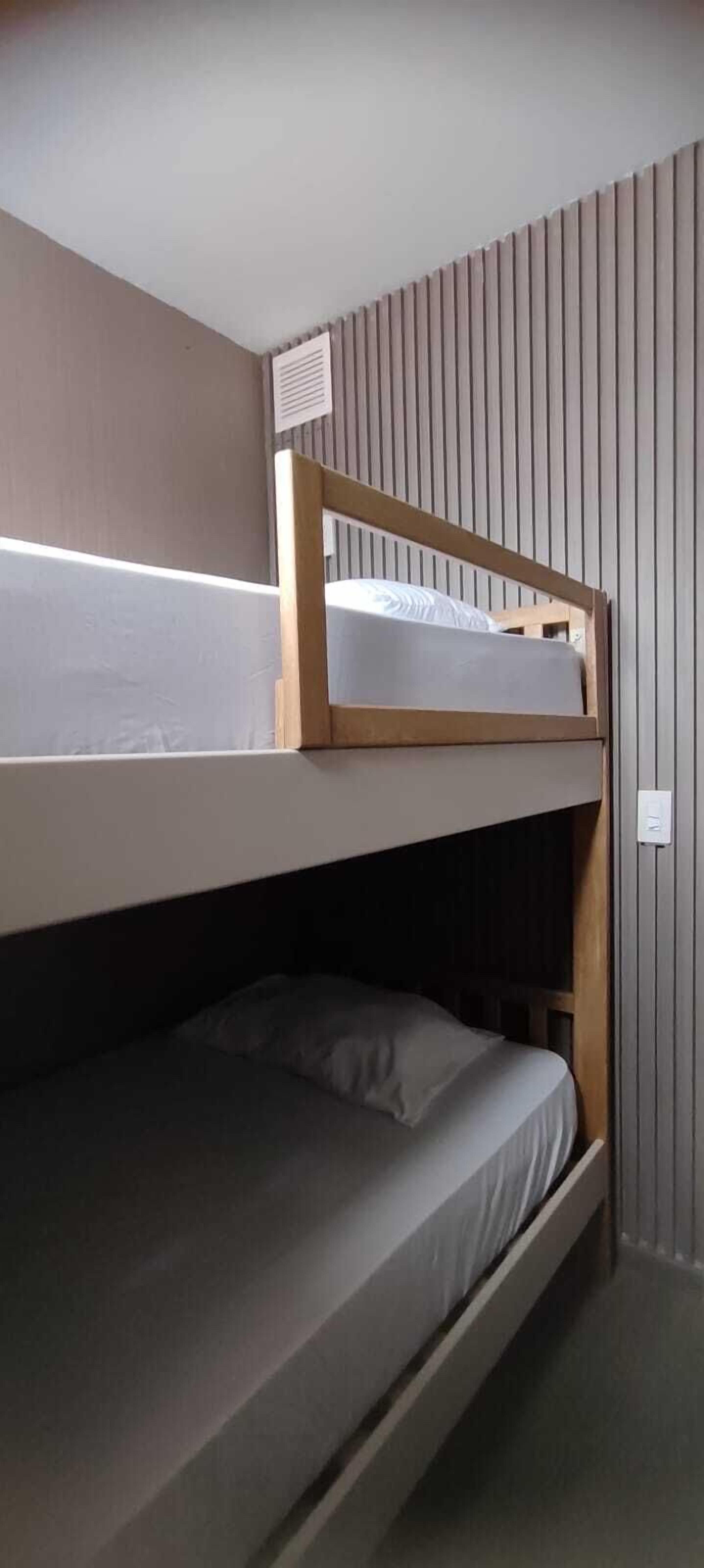 A bunk bed room with a sloped ceiling and vertical paneling on the walls.