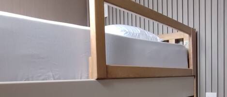 A bunk bed room with a sloped ceiling and vertical paneling on the walls.