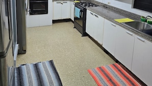 Una cocina compacta con armarios blancos, un horno negro, un microondas, una estufa a gas y un refrigerador.