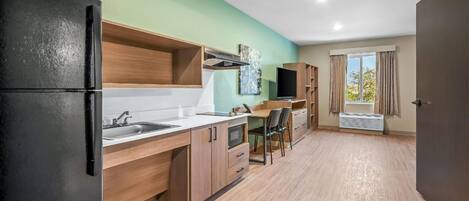 A modern kitchen with a refrigerator, sink, and wooden cabinets.