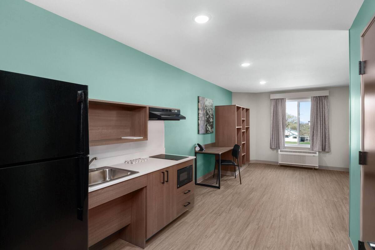 Una cocina moderna con refrigerador, lavamanos y armarios de madera.
