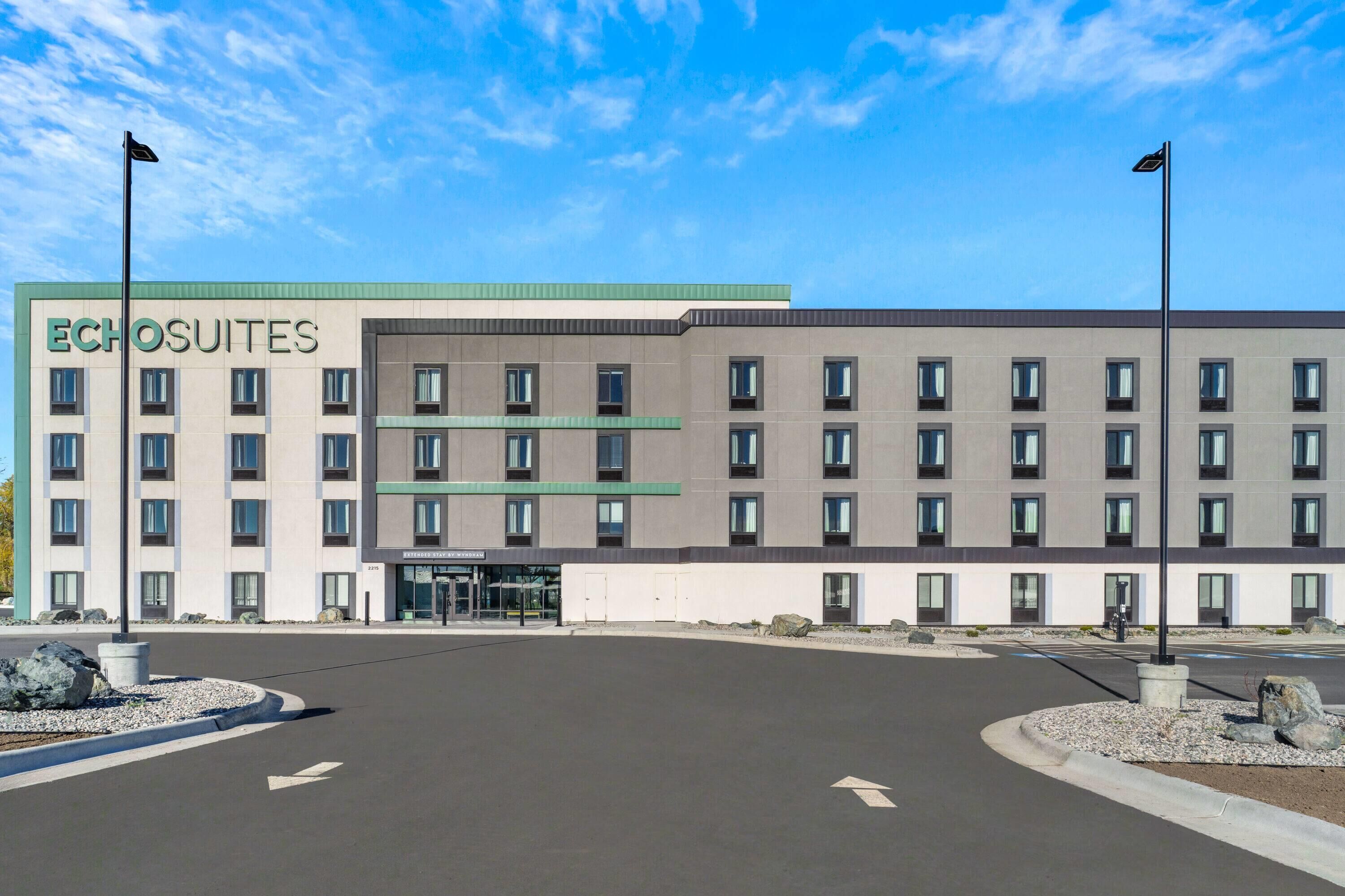 A modern hotel building with a flat roof, multiple windows, and a sign reading 'Echosuites.'