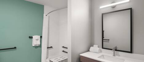 A modern bathroom with a shower, a sink, and a mirror.