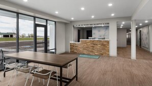 A modern interior with a reception desk, a wooden table with chairs, and large windows. - Echo Suites Extended Stay By Wyndham Bozeman (Bozeman)