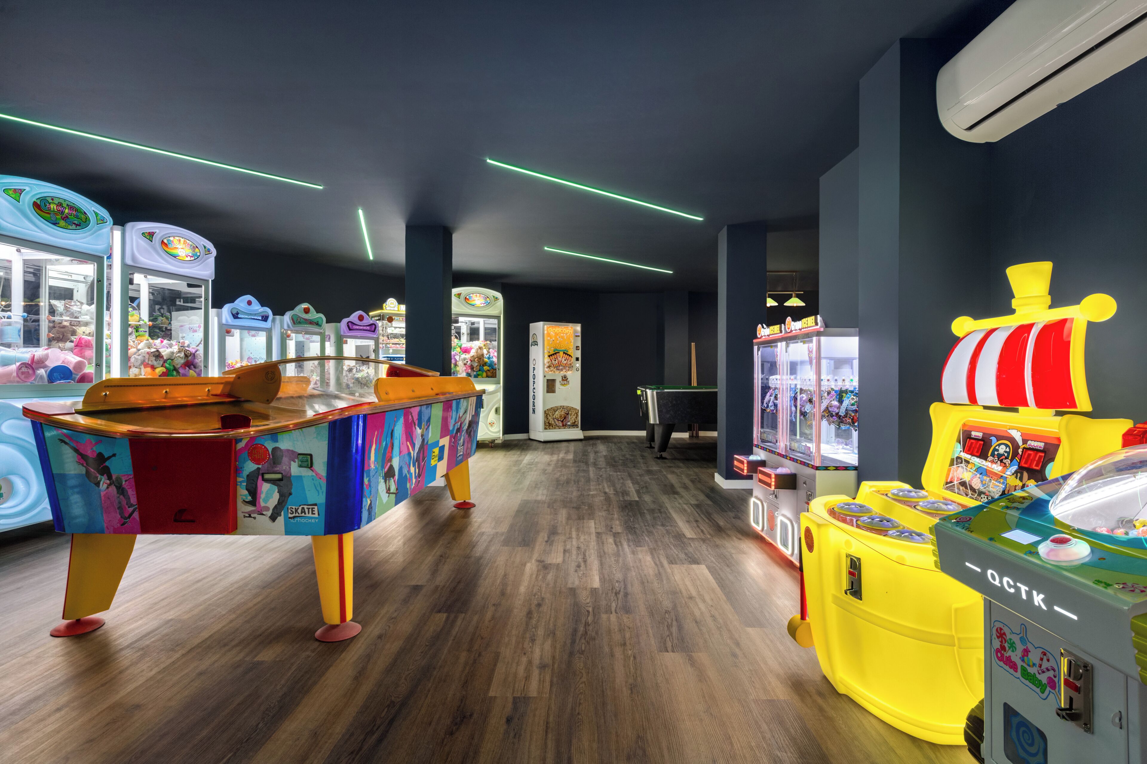 A brightly lit arcade with various gaming machines and a colorful table tennis table.