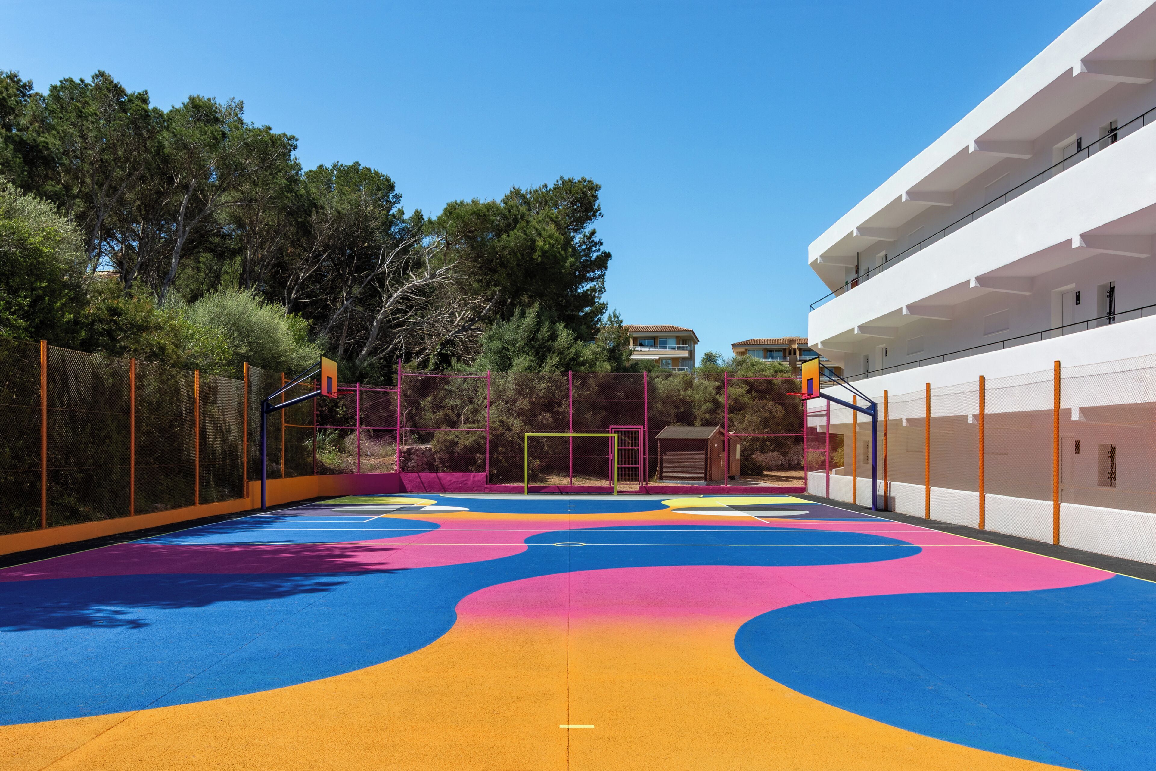 Un parque infantil con piso de goma de colores y vallas de seguridad.
