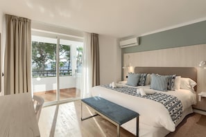 Una habitación de hotel con una cama, un banco, un escritorio y vistas al exterior.