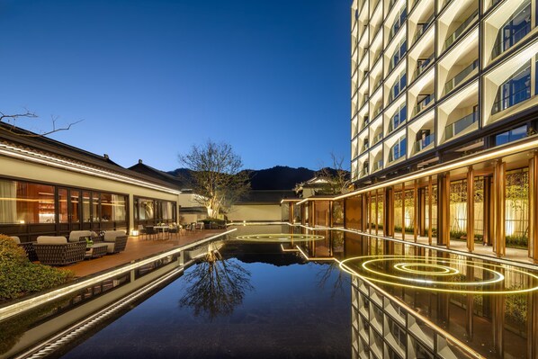 A modern hotel with a reflective pool, outdoor seating, and traditional architecture. - Wyndham Grand Tengchong Hot Spring (Baoshan)