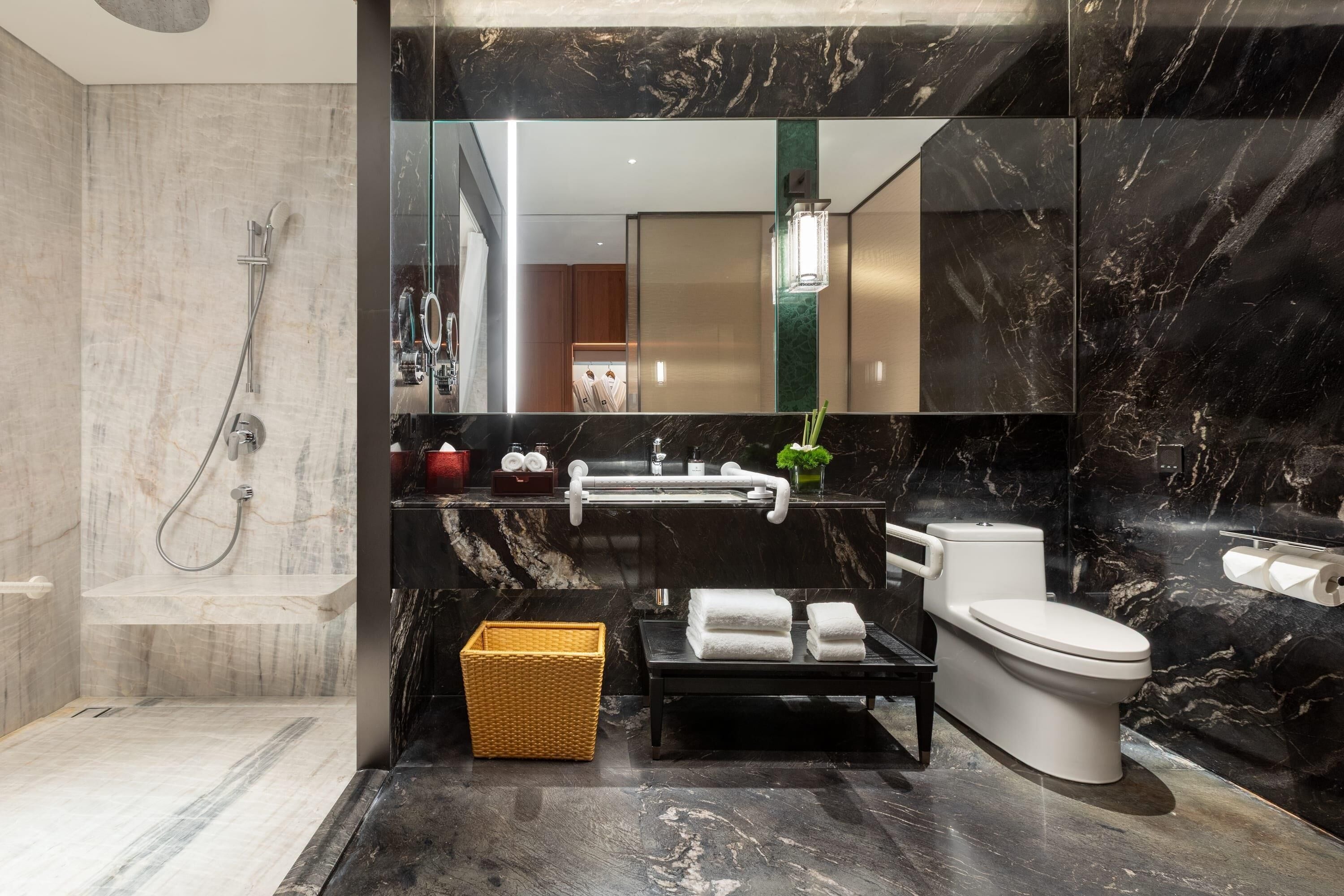 A modern bathroom with a marble shower, a toilet, and a sink.