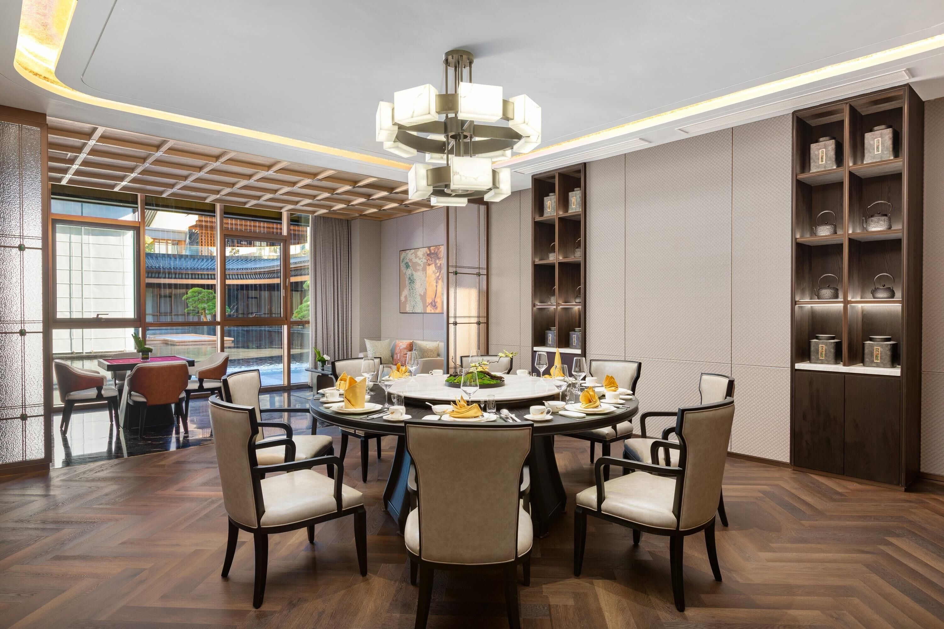 A dining area with a round table set for six, surrounded by six chairs.