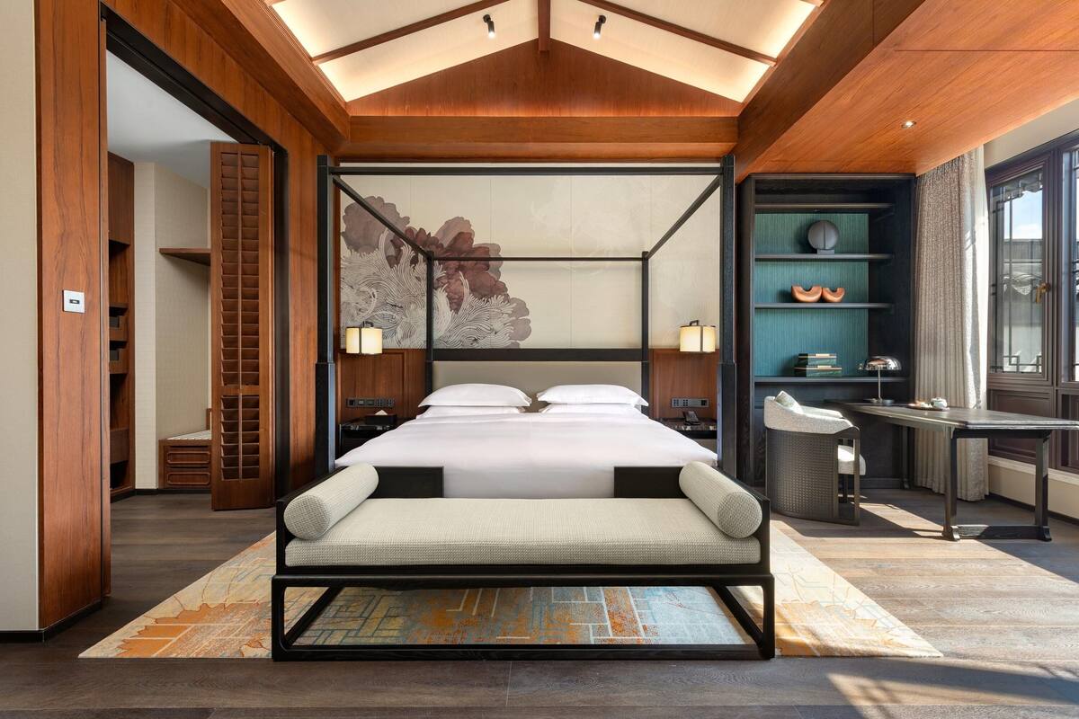 Una habitación de hotel moderna con una cama grande, un escritorio y vistas al exterior.