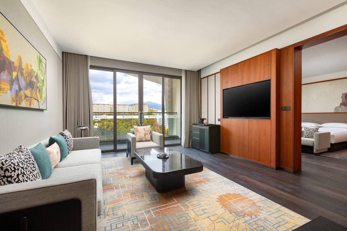 Una habitación de hotel moderna con una cama grande, un sofá, una mesa de centro y un televisor.