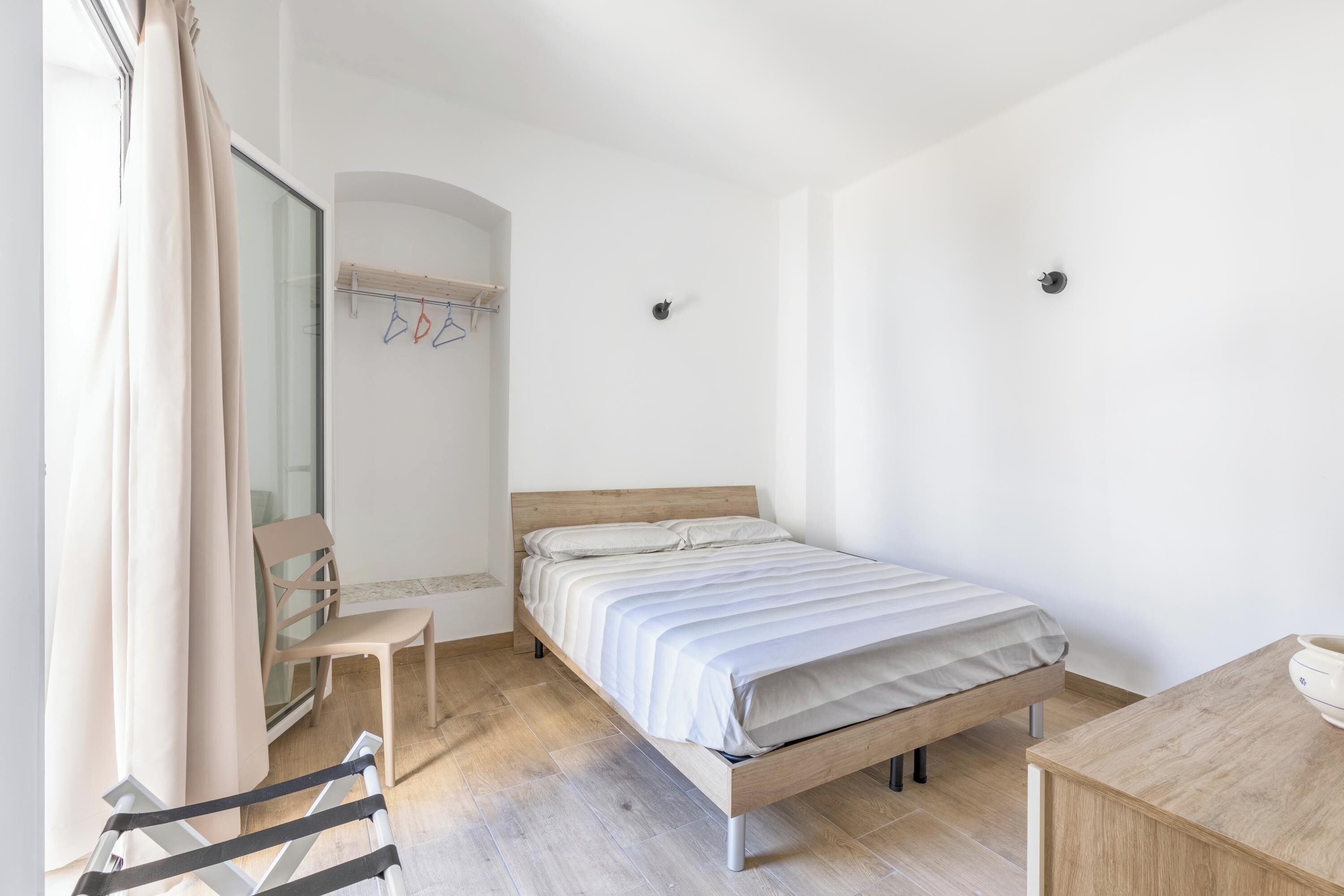 Een slaapkamer met een bed, een stoel, een bureau en een kledingkast.