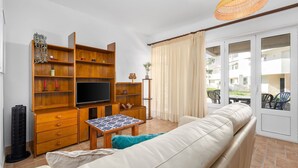 Een woonkamer met een bank, televisie, houten planken en een kleine tafel.