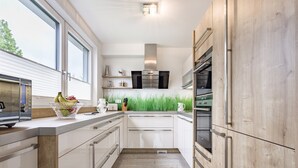 A modern kitchen with white cabinetry, a stainless steel range hood, and a window providing natural light. - Luxury Apartment Silvia, Lake view & Terrace (Zell am See)
