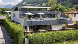 A modern two-story building with a balcony, large windows, and a view of a mountainous landscape. - Luxury Apartment Silvia, Lake view & Terrace (Zell am See)