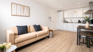 En moderne stue med en beige sofa, et sofabord og et spiseområde med et træbord og stole.