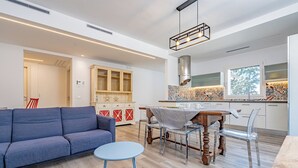 Un soggiorno moderno con un divano blu, un tavolino piccolo rotondo e una zona pranzo con un tavolo in legno e sedie.