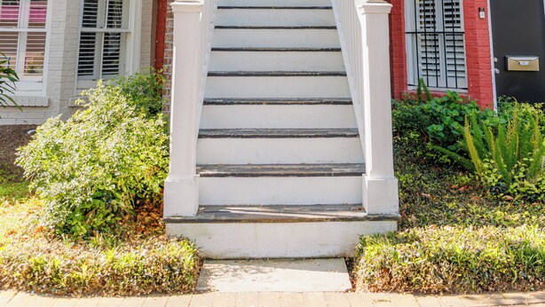 A two-story building with a red door and white steps leading to the entrance.