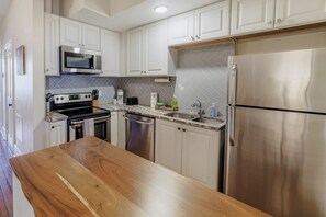 Una cocina moderna con armarios blancos, electrodomésticos de acero inoxidable y encimera de madera.
