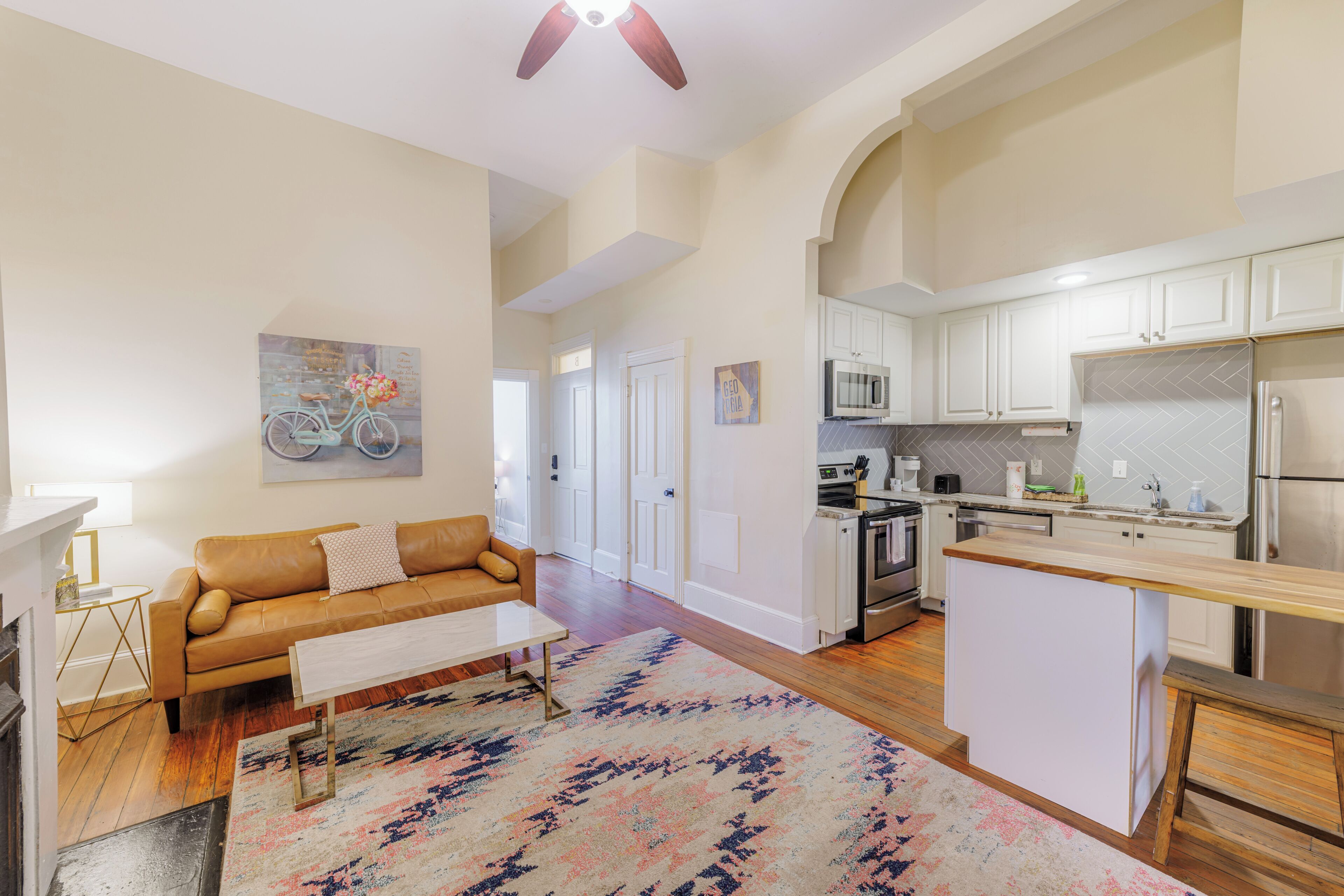 A modern kitchen with white cabinets, stainless steel appliances, and a wooden island.