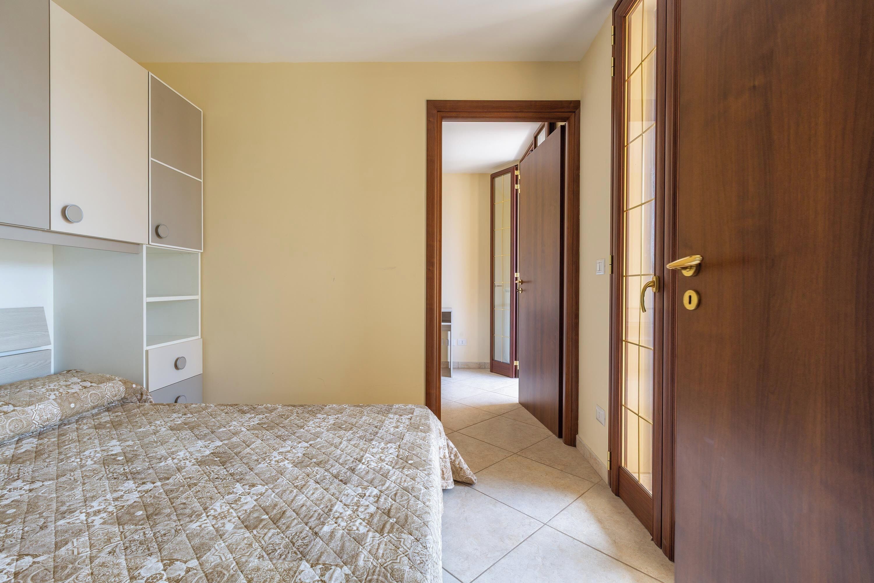 Ein Schlafzimmer mit Bett, Kleiderschrank und einer Tür zu einem anderen Raum.