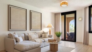 A modern living room with a beige sectional sofa, a round coffee table, and two framed artworks on the wall. - Crescent Beach by Otium (Humacao)