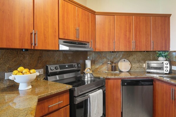 A kitchen with wooden cabinets, a stainless steel stove, a dishwasher, a toaster, and a bowl of lemons. - Crescent Beach by Otium (Humacao)