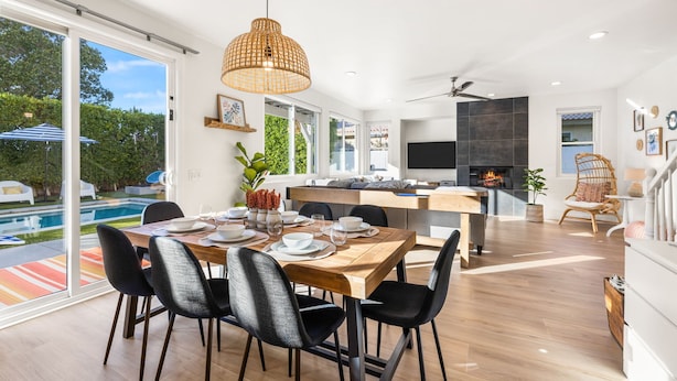 A modern kitchen with a dining area, large windows, and a view of a swimming pool. - Wren by Nest Villas | Private Pool, Spa & Firepit (Indio)
