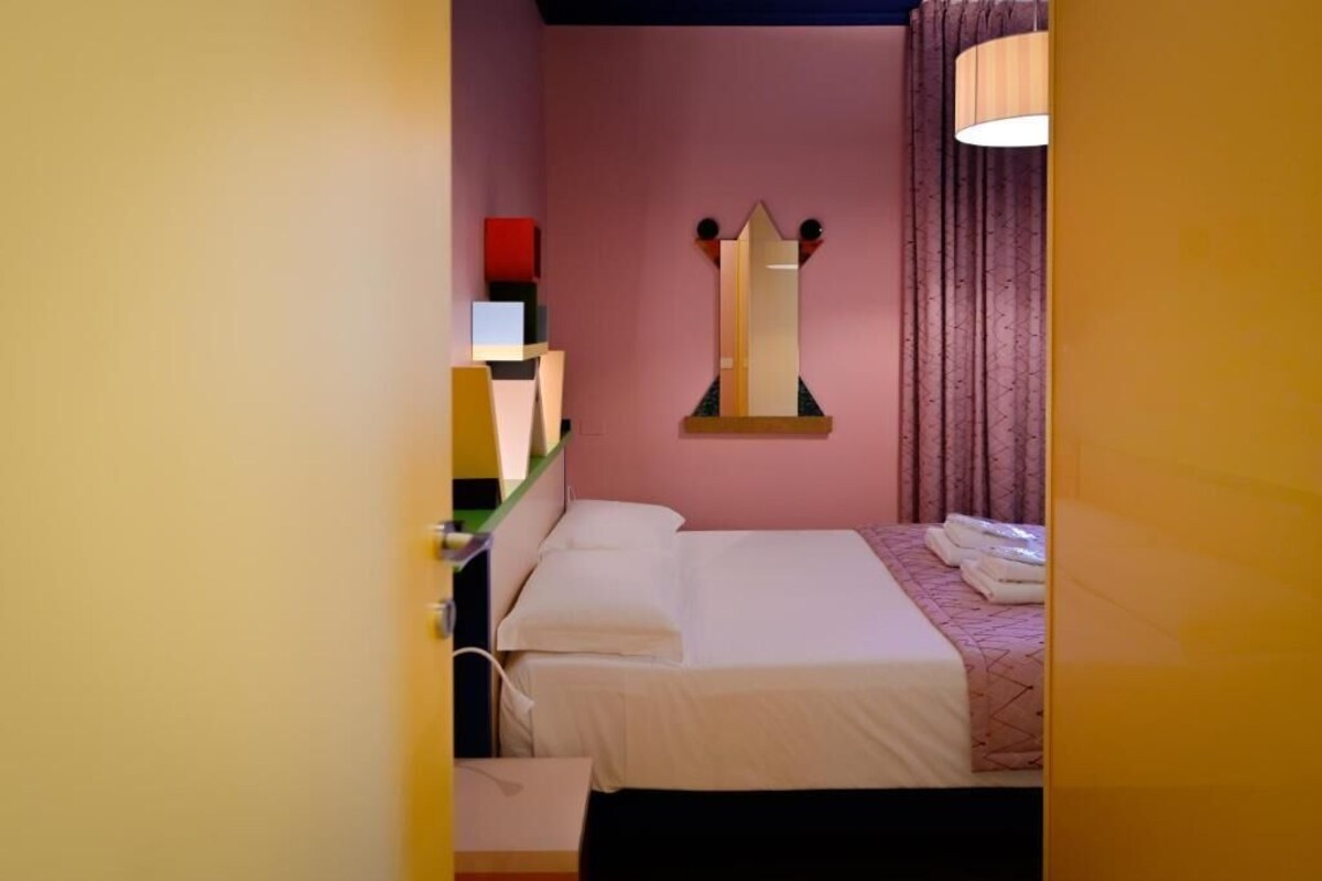 Habitació d'hotel amb un llit, un mirall i una làmpada.