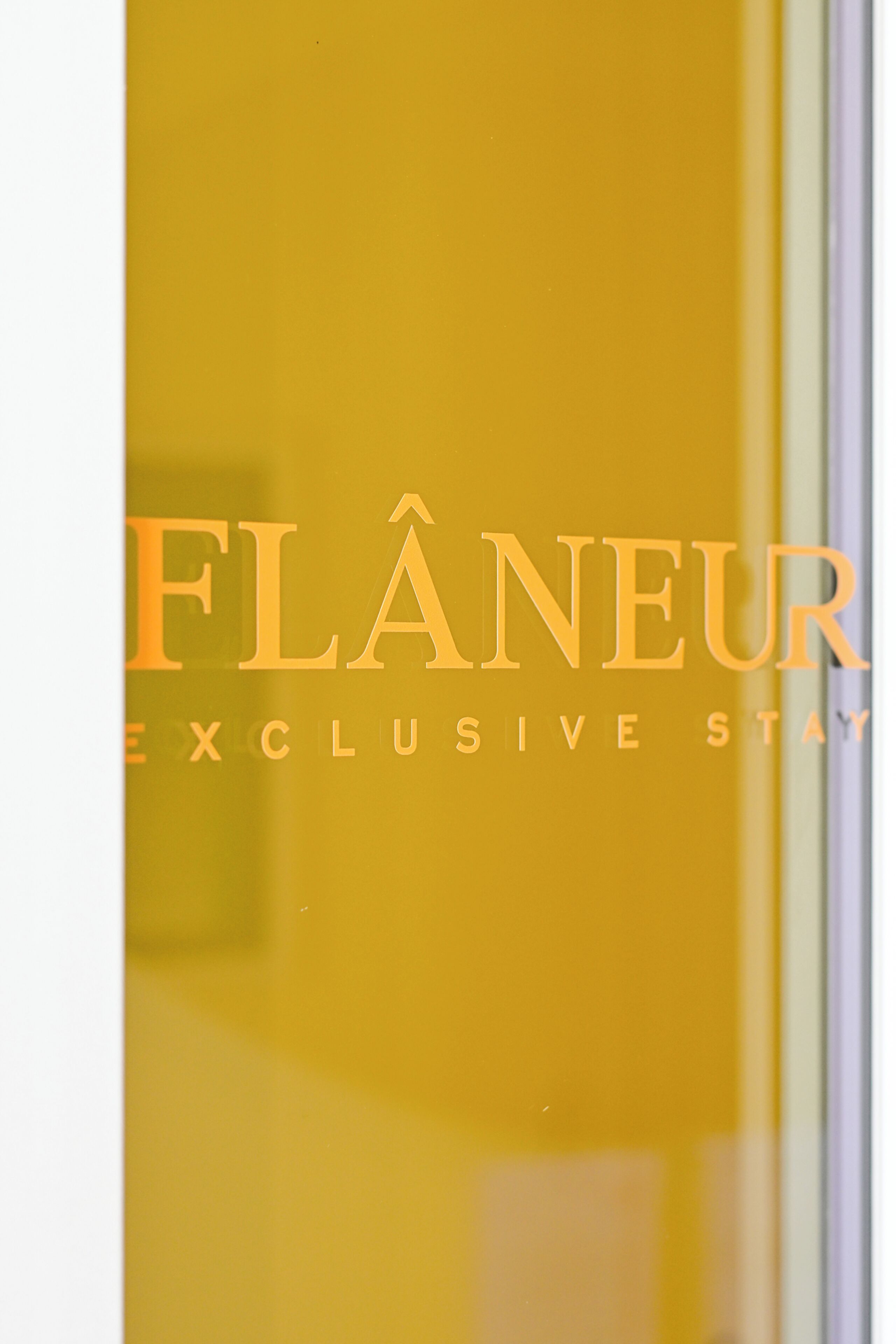 A hotel sign with the name 'FLÂNEUR' and the words 'EXCLUSIVE STAY' below it.