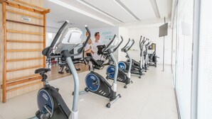 Ett gym med motionscyklar, en trästege och en vägg täckt med speglar.