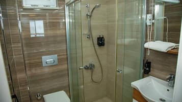A modern bathroom with a glass-enclosed shower, a white toilet, and a sink with a mirror above it.