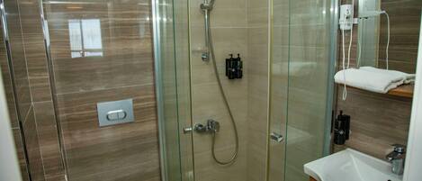 A modern bathroom with a glass-enclosed shower, a white toilet, and a sink with a mirror above it.