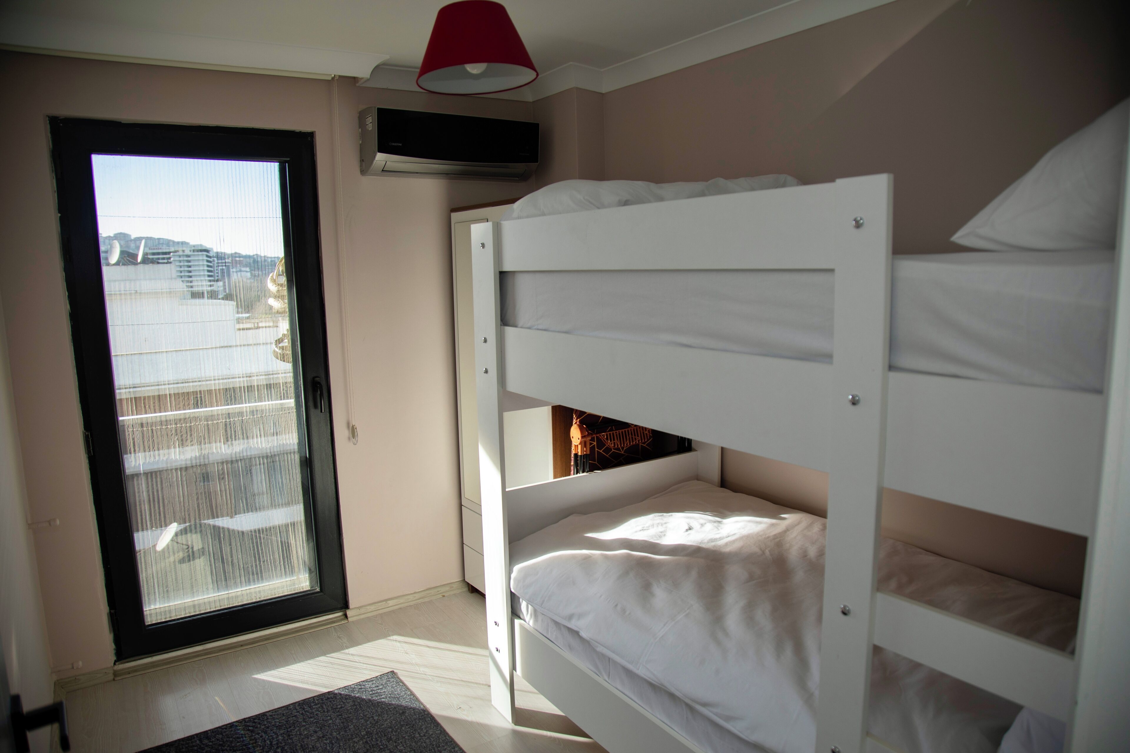 A room with a bunk bed, a sliding door to a balcony, and a ceiling-mounted air conditioning unit.