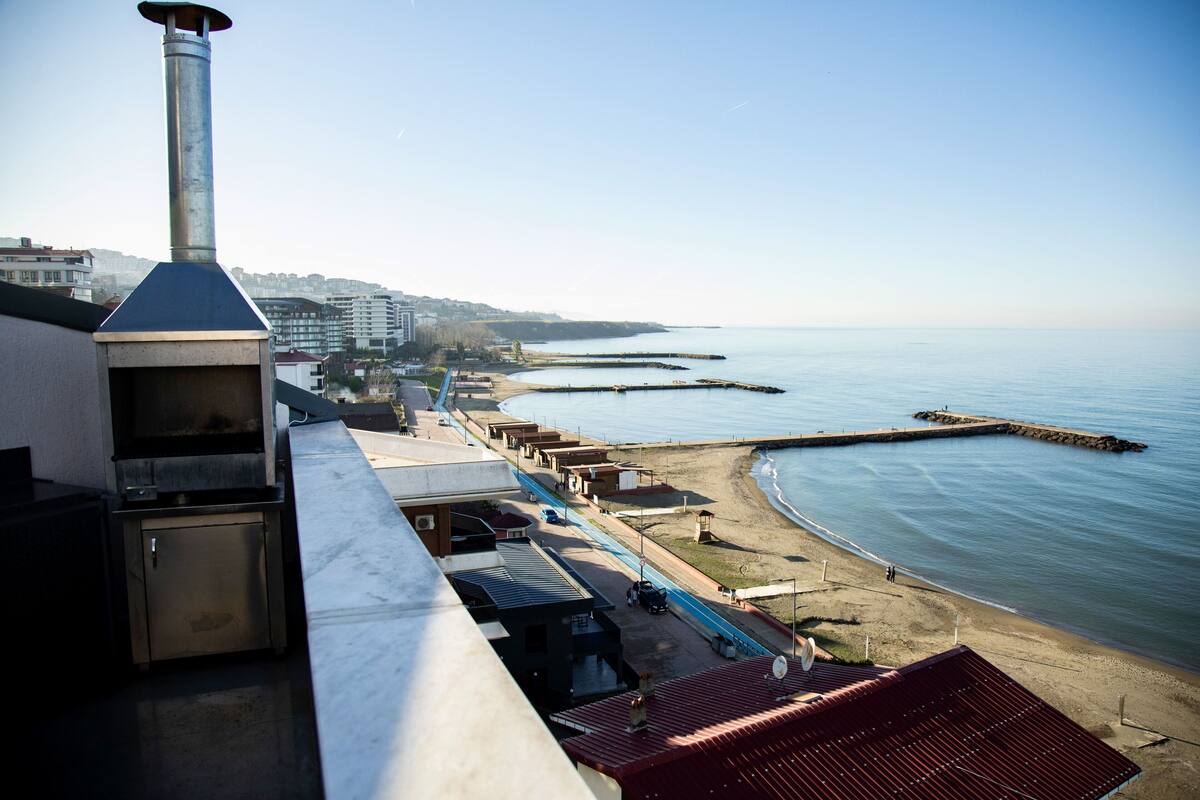 Vistes costaneres amb una platja, un moll i un edifici amb una xemeneia.