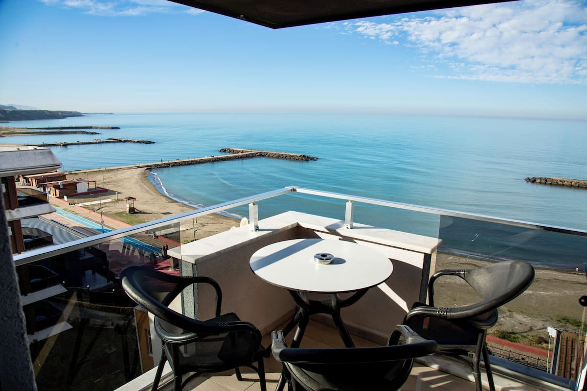 Un balcó amb taula i cadires amb vista a una platja i mar tranquil·la.