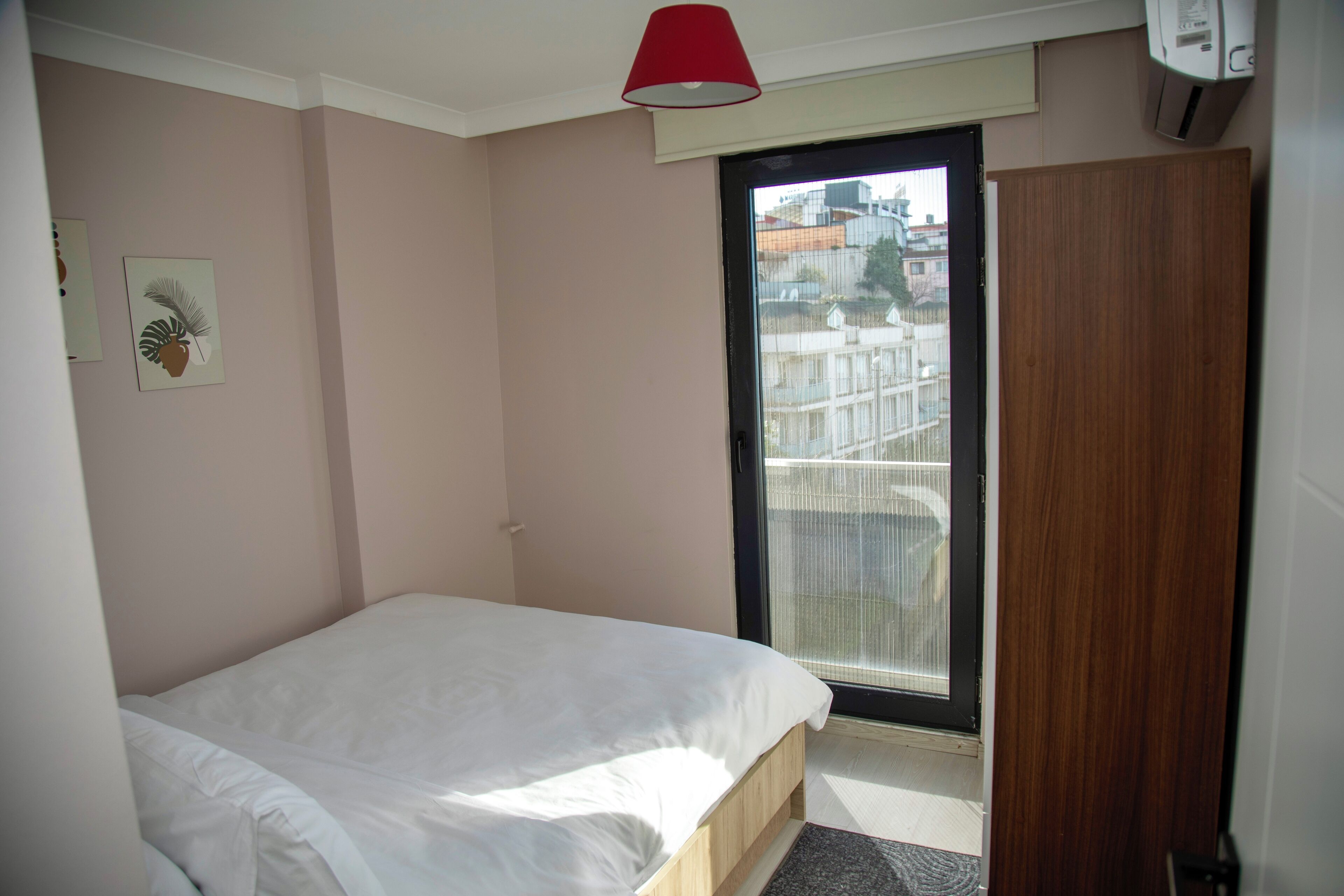 A bedroom with a bed, a door, and a window.