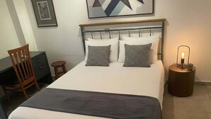 A neatly made bed with a grey blanket, two patterned pillows, and a bedside lamp. - Triple Nest Maisonette – Korydallos by ΜΡS (Koridallos)
