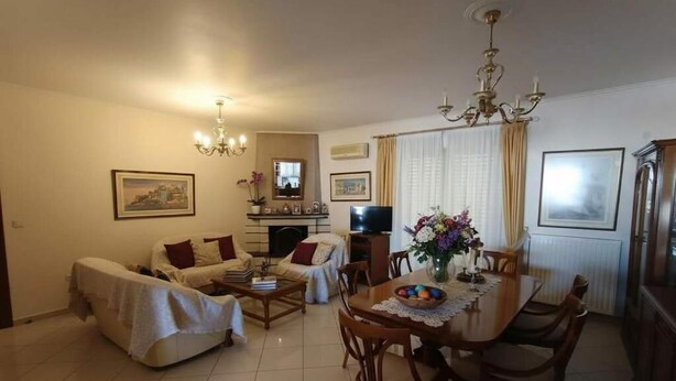 A living room with a sofa, a dining table with chairs, a TV, and a chandelier. - Triple Nest Maisonette – Korydallos by ΜΡS (Koridallos)
