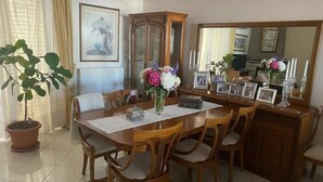 A dining area with a wooden table, chairs, a vase with flowers, a cabinet, and a mirror. - Triple Nest Maisonette – Korydallos by ΜΡS (Koridallos)