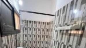 A small bathroom with a toilet, sink, and mirror. The walls are tiled with a checkered pattern.