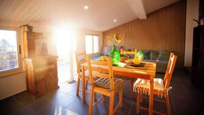 Een eetgedeelte met een houten tafel en stoelen, een groene fles en een vaas met bloemen.