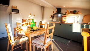 Een kleine keuken met een eettafel, stoelen, een magnetron en een fornuis.