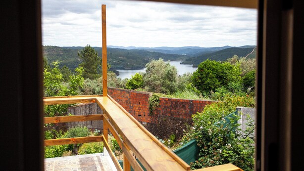 Une vue depuis un balcon donnant sur un lac, entouré de verdure et de collines.