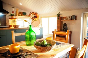 Una mesa de comedor con un tazón de aguacates, una botella verde y una taza amarilla.