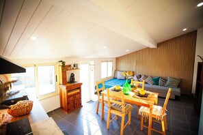 Amplia sala de estar con mesa de comedor, sillas, sofá y cocina con armarios de madera y encimera.
