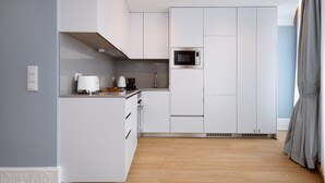 A modern kitchen with white cabinetry, a microwave, and a coffee maker. - Charming Studio for 4 in Historical Center (Oporto)