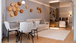 A modern living room with a dining area, featuring a sofa, chairs, a coffee table, and a wall adorned with hats. - Charming Studio for 4 in Historical Center (Oporto)